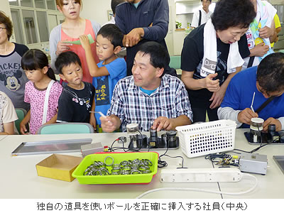 独自の道具を使いボールを正確に挿入する社員(中央)