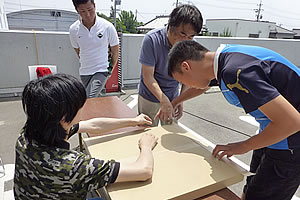 箱の合わせ目にテープを貼る梱包作業